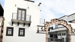 A building with a white facade, a balcony, and a gated entrance. - Loreto80– Studio Palo Blanco (Loreto)