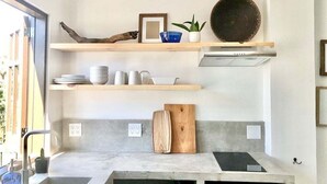 A modern kitchen with a built-in stove, a wooden cutting board, and a shelf with kitchenware. - Loreto80– Studio Palo Blanco (Loreto)
