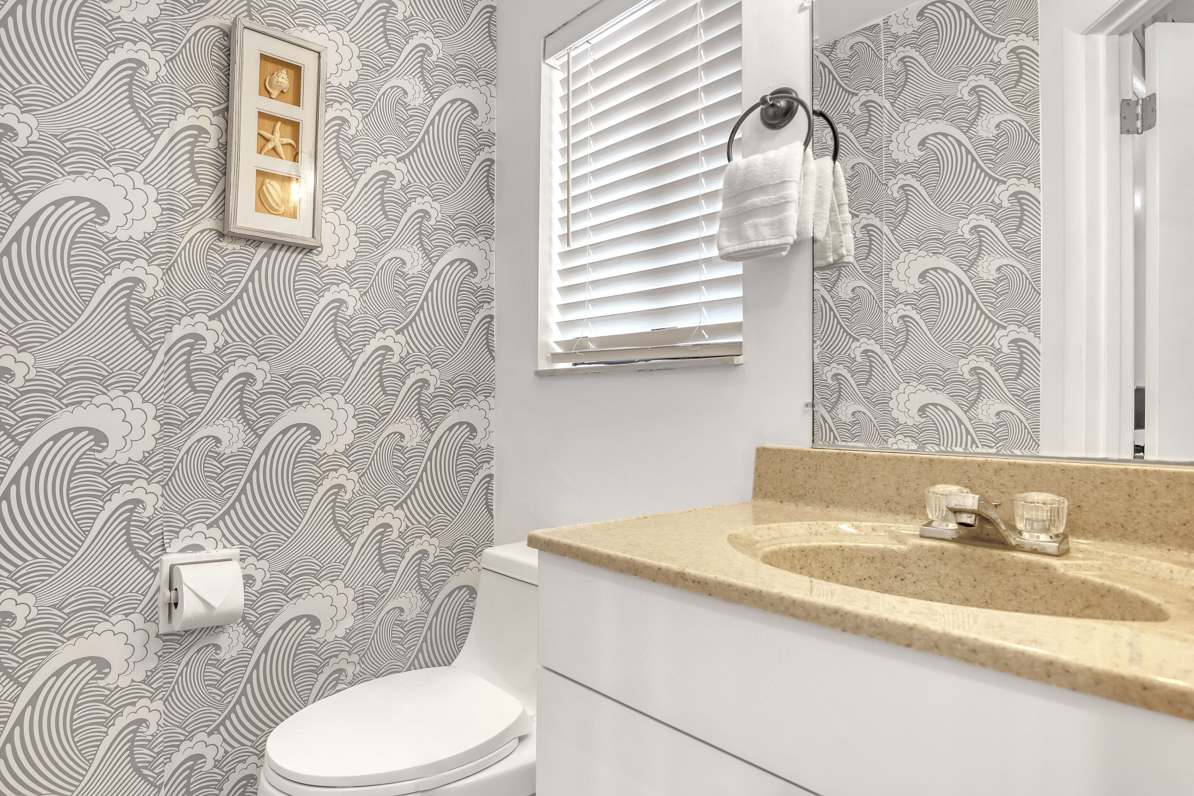 A bathroom with a toilet, sink, and mirror.