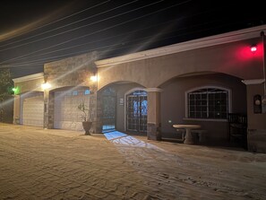 A building with multiple garage doors, a potted plant, and a bench outside. - San Felipe Place To Stay B&B (San Felipe)