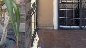 A building entrance with a metal gate, a potted plant, and a sign indicating the street name and number. - San Felipe Place To Stay B&B (San Felipe)