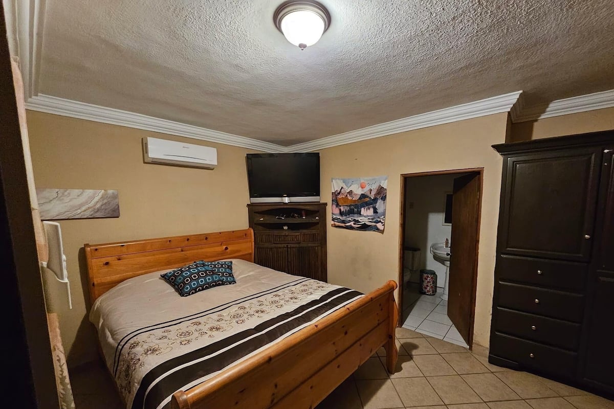 A bedroom with a wooden bed, a television, a painting, and a wardrobe.