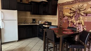 A kitchen with dark cabinets, a white refrigerator, a stove, and a dining table with chairs. - San Felipe Place To Stay B&B (San Felipe)