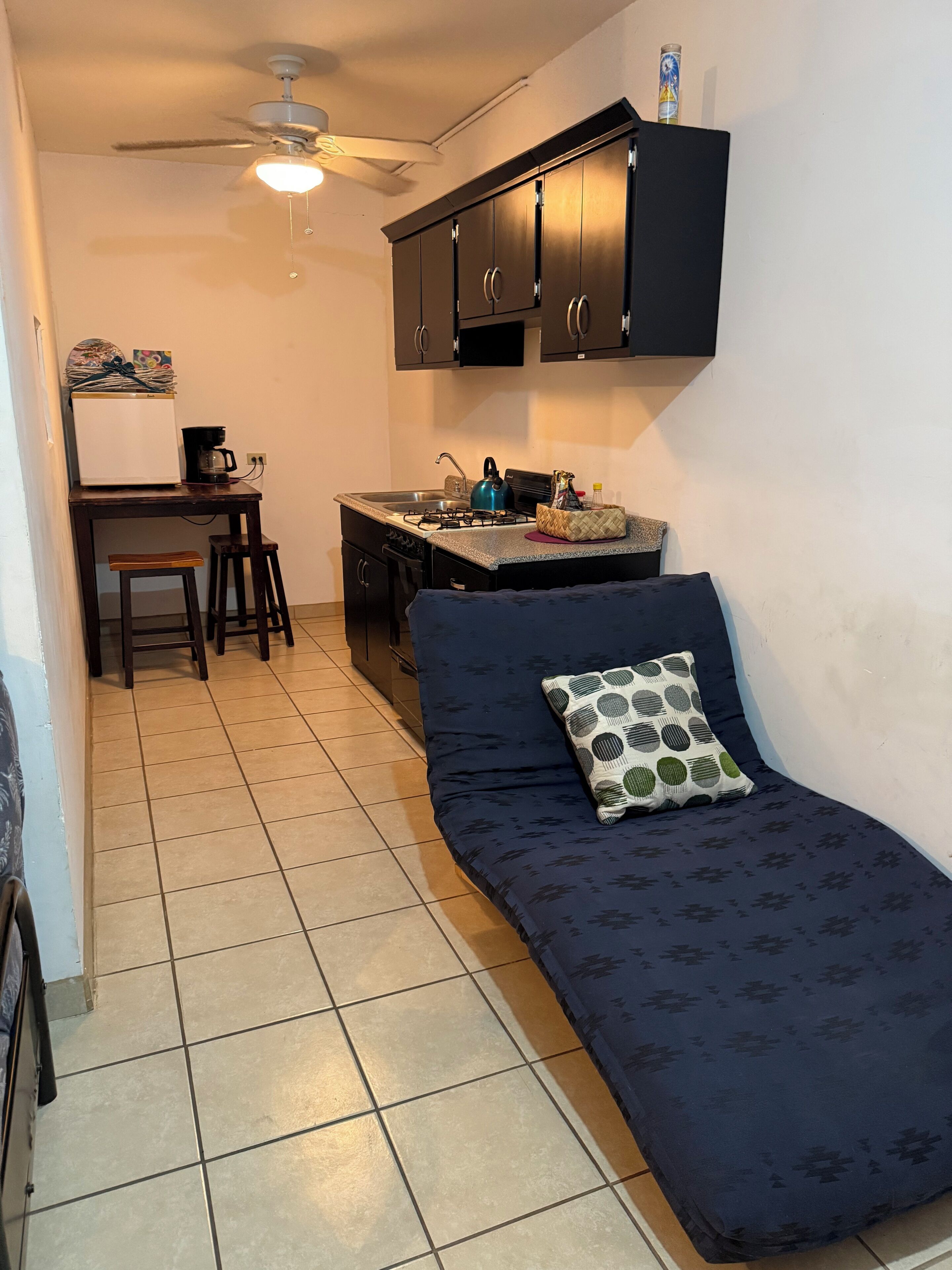 A compact kitchenette with a stove, sink, and a small dining area.