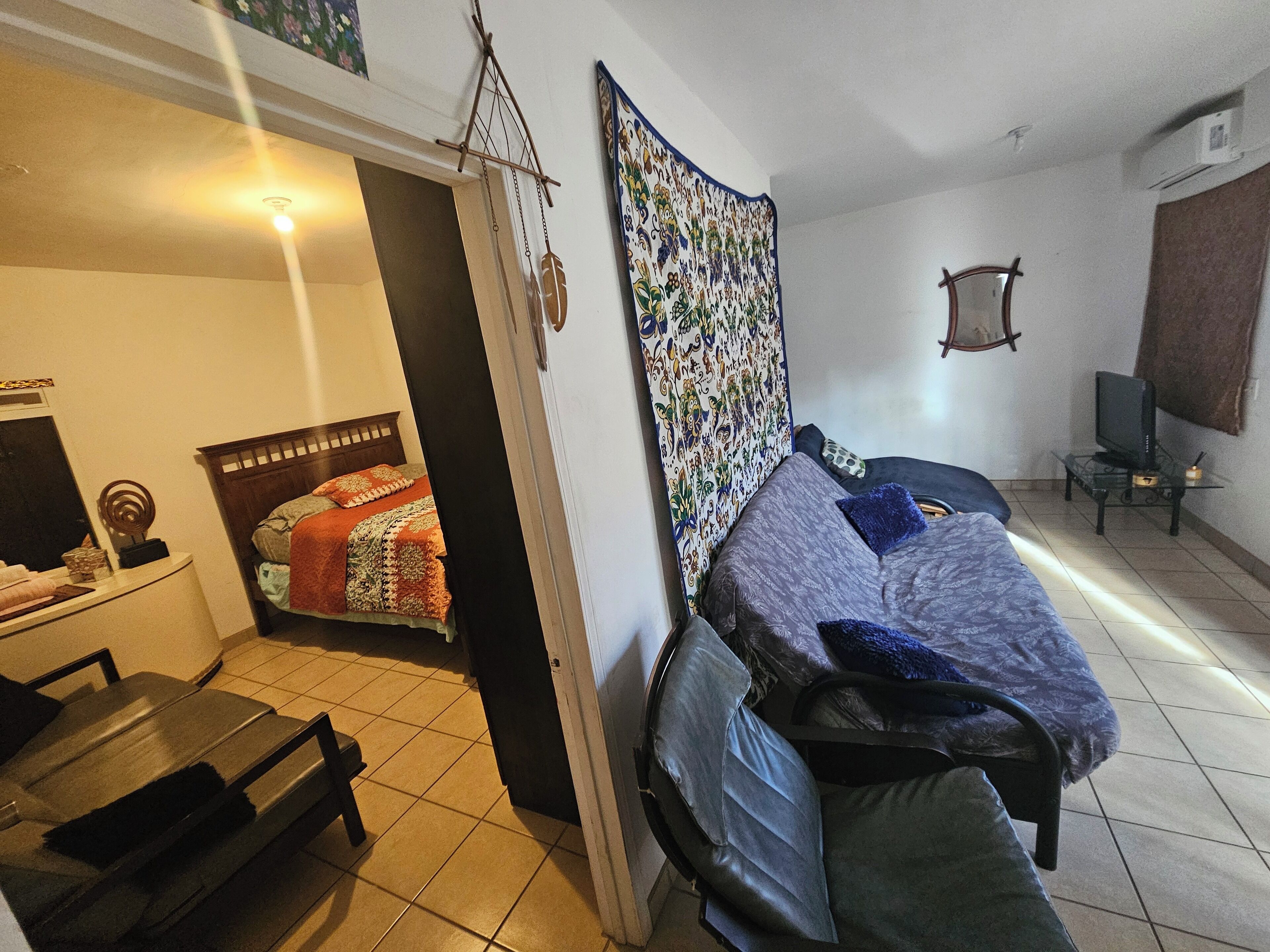Een kamer met een bed, een stoel, een bureau en een televisie.