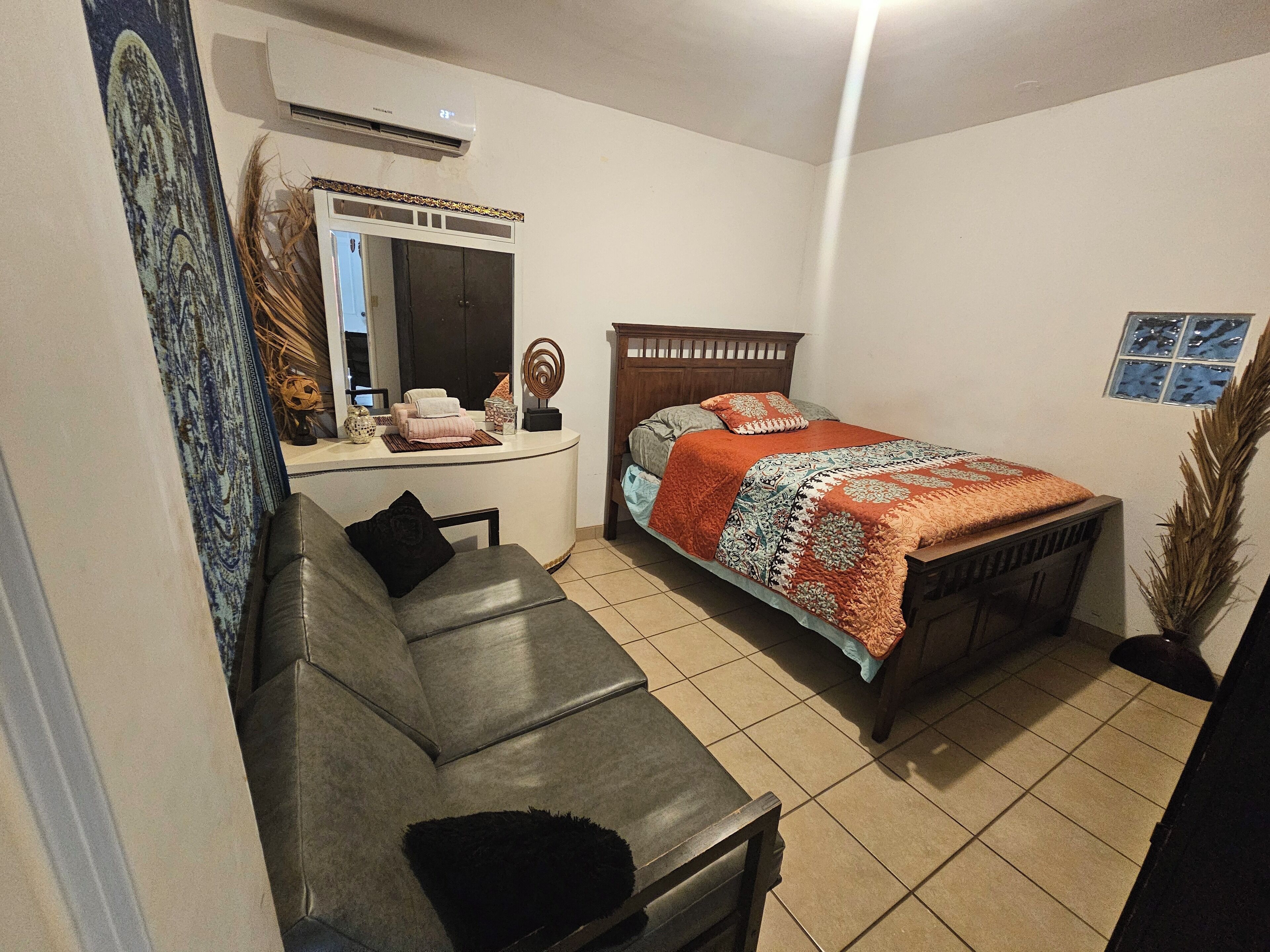 Une chambre à coucher avec un lit, un canapé, une table de chevet et un miroir.