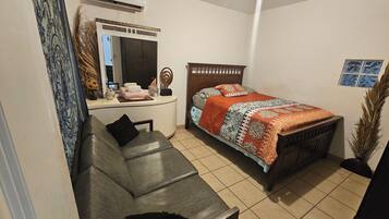 Une chambre à coucher avec un lit, un canapé, une table de chevet et un miroir.