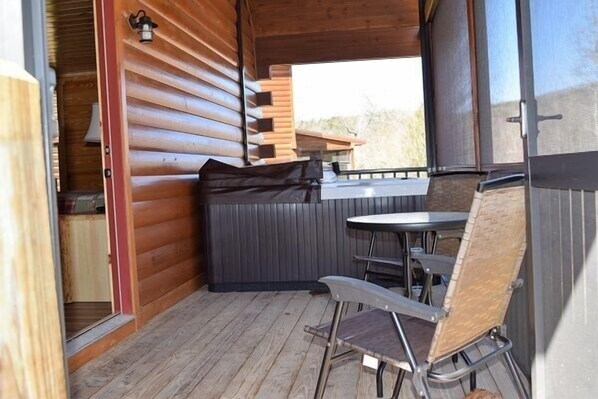 A wooden cabin with a small patio area featuring a table and chairs.