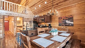 Un interior rústico de madera con cocina, comedor y una escalera que sube a un nivel superior.