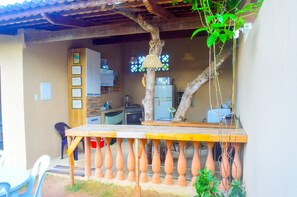 A rustic outdoor area with a wooden table, terracotta balustrades, and a hanging light fixture.