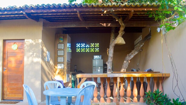 Une terrasse avec une table et des chaises en bois, une porte en bois et une rambarde décorative.