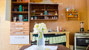 Une cuisine avec des meubles en bois, un fourneau et une table agrémentée d’un vase de fleurs.
