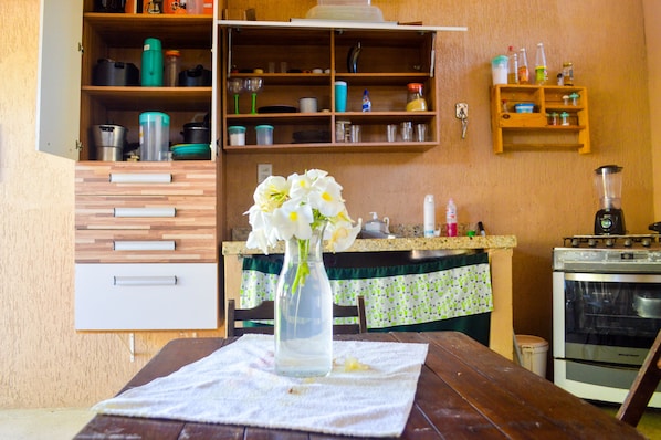 A kitchen with wooden cabinets, a stove, and a table with a vase of flowers.