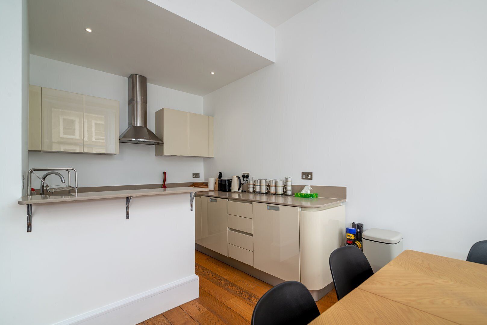 A modern kitchen with a built-in stove, a sink, and a dining area with a table and chairs.