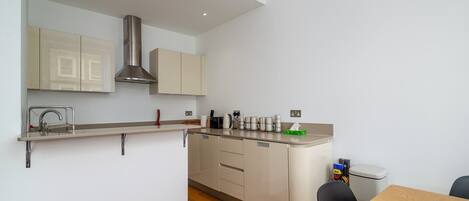 A modern kitchen with a built-in stove, a sink, and a dining area with a table and chairs.