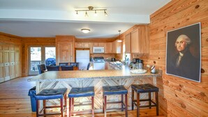 A kitchen with wooden cabinets, a granite countertop, and a central island with bar stools. - Cabin 115, Luxury 6 bedroom, 3 bath cabin minutes from Downtown Lexington!  (Lexington)