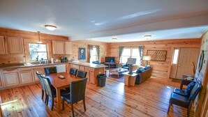 A spacious cabin with a wooden interior, a dining area, a kitchen, a living room, and a fireplace. - Cabin 115, Luxury 6 bedroom, 3 bath cabin minutes from Downtown Lexington!  (Lexington)