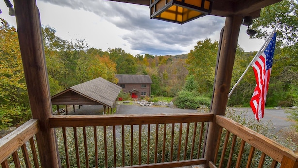 A wooden deck with a view of a cabin and a flag. - Cabin 115, Luxury 6 bedroom, 3 bath cabin minutes from Downtown Lexington!  (Lexington)