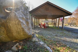 En överbyggd paviljong med ett bord och stolar, en amerikansk flagga och en stor sten i närheten.