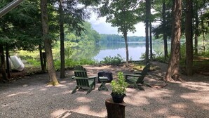 A campsite with green Adirondack chairs, a picnic table, and a potted plant.