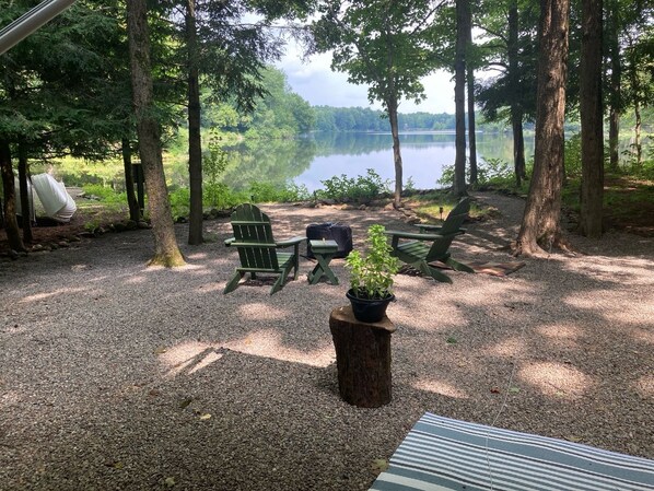 A campsite with green Adirondack chairs, a picnic table, and a potted plant.