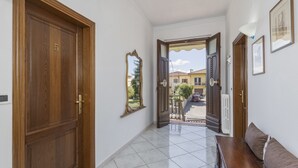 Um corredor com porta de madeira, espelho e um banco.