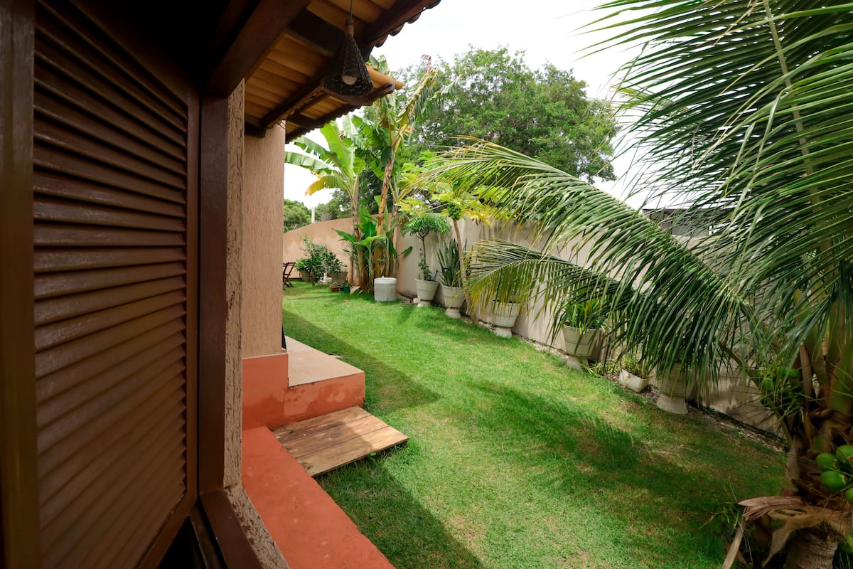 A view of a backyard with a wooden deck, a small garden area with potted plants, and a palm tree.