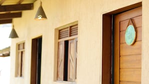 Fachada de edificio con puertas y ventanas de madera, un letrero colgante e iluminación colgante.