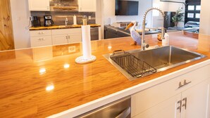 A modern kitchen with a wooden countertop, stainless steel sink, and white cabinets. - Gulf Access Resort Style Pool Home Only 4 minutes to the Beach (Bonita Springs)