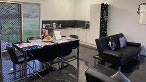 Una cocina moderna con armarios blancos, encimera negra y un comedor con una mesa dispuesta para cuatro.