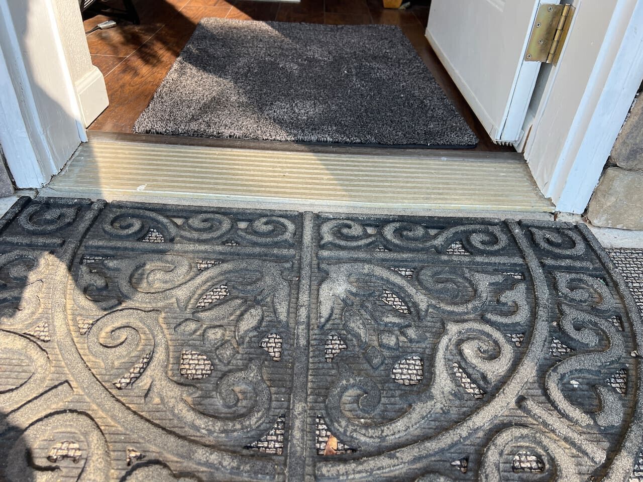 Uma porta com soleira metálica decorativa e um tapete.