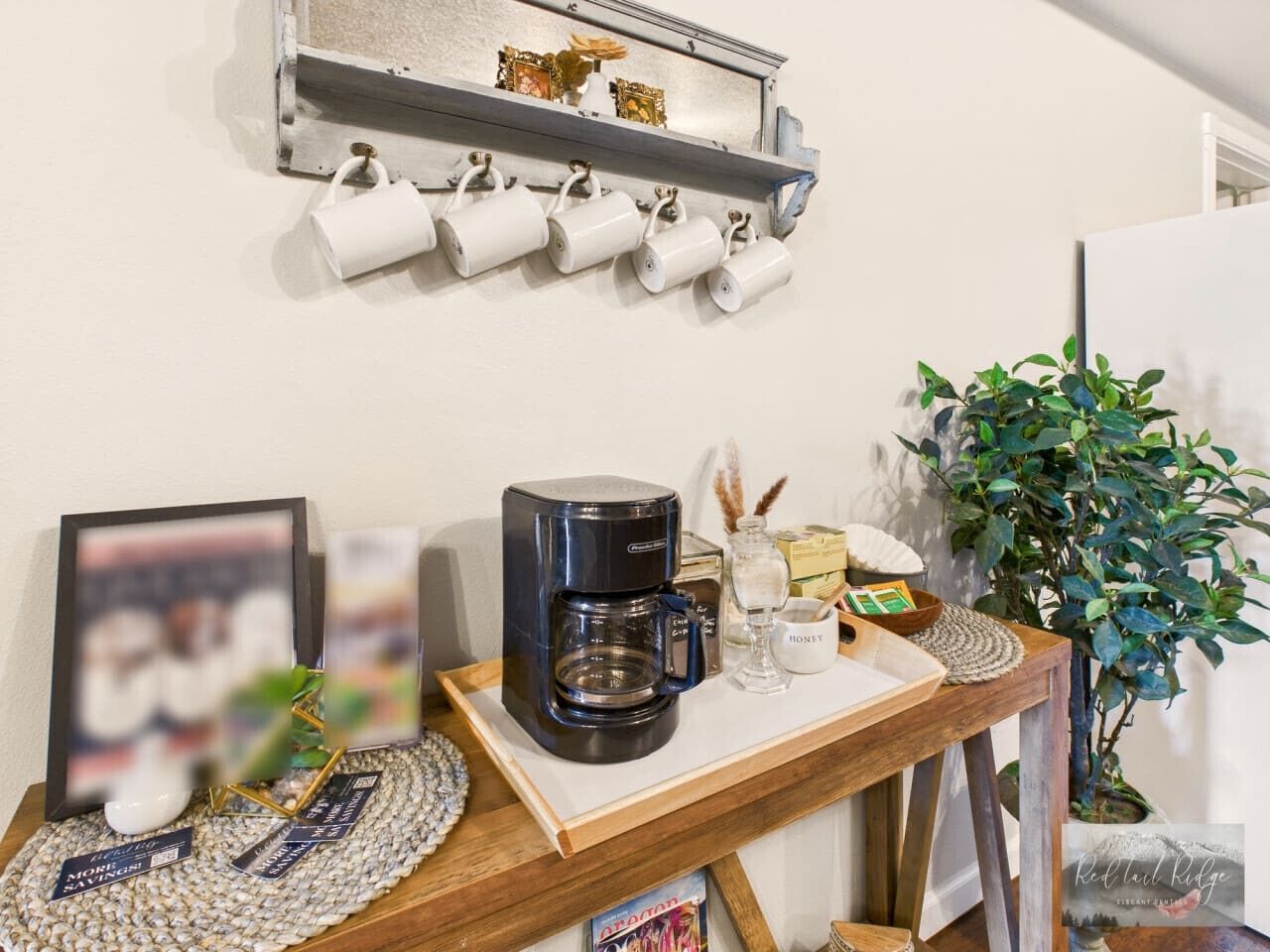 Un coin café équipé d’une machine à café, de tasses et d’un plateau contenant du miel et des sachets de thé.