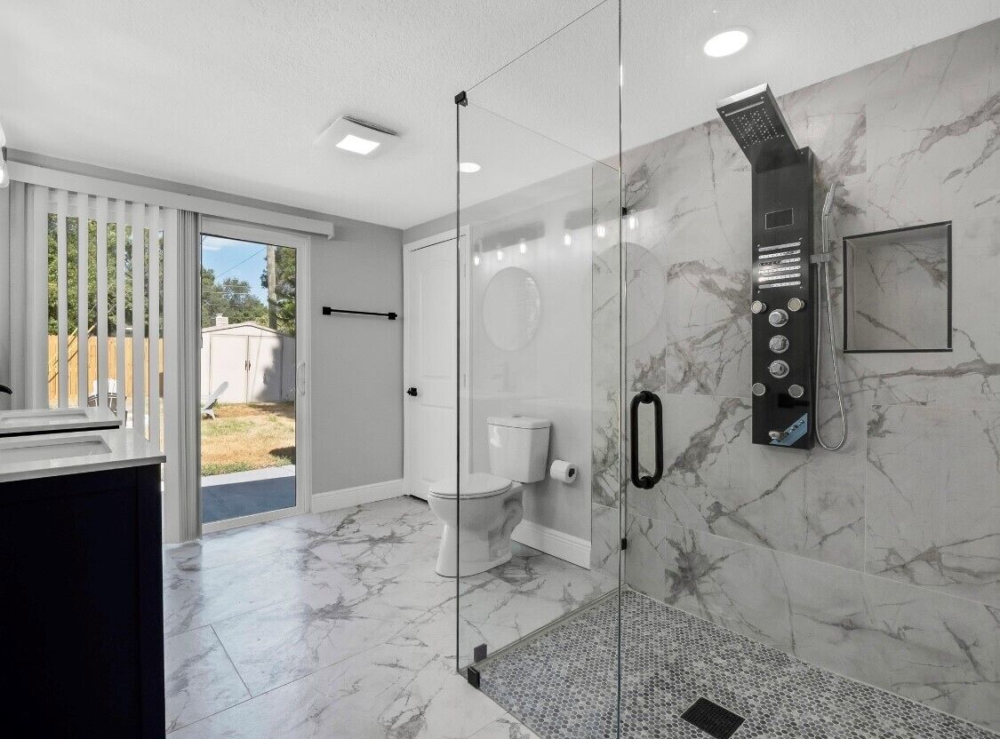 A modern bathroom with a glass-enclosed shower, a toilet, and a sink.