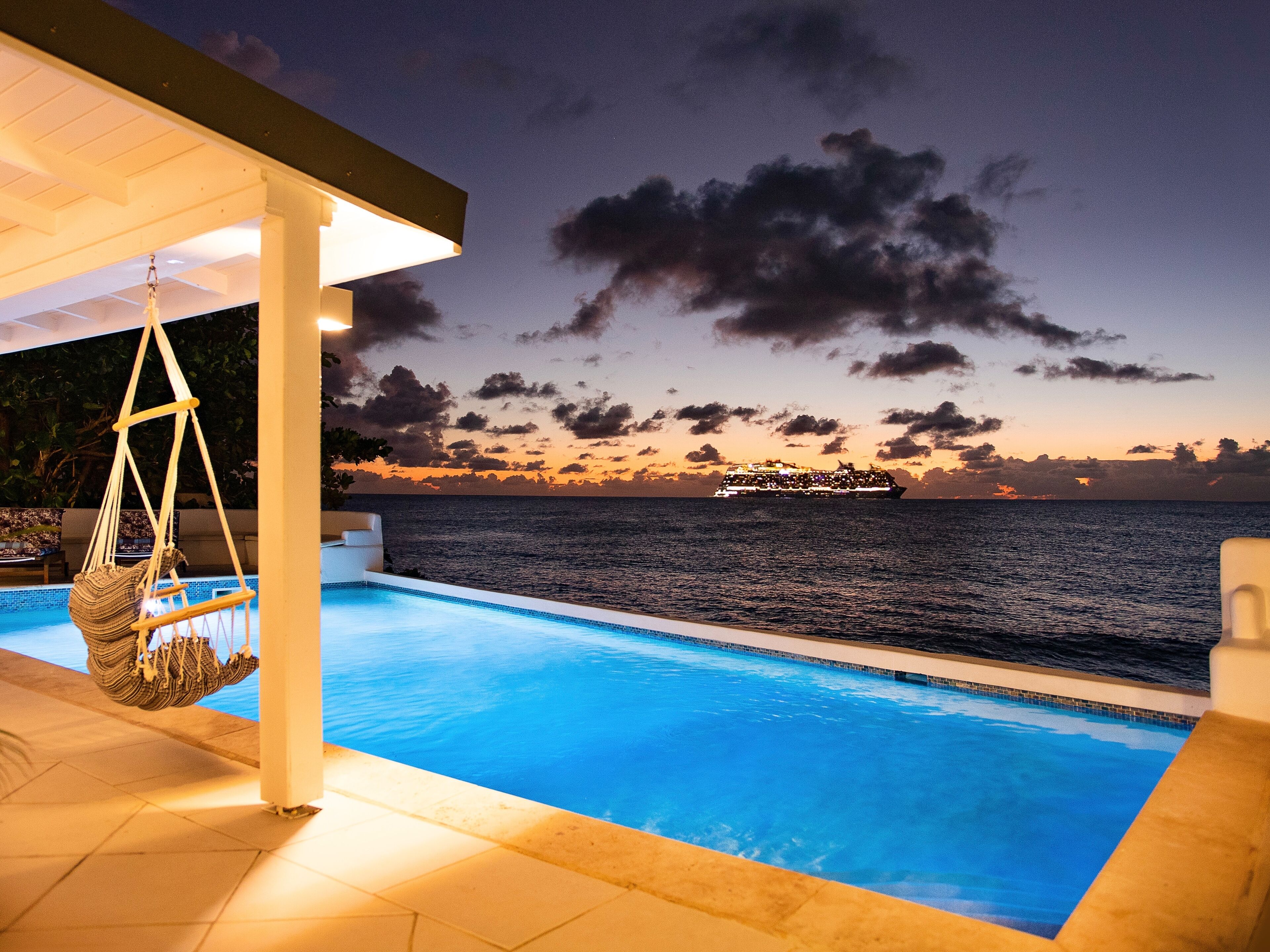 A pool with a view of the ocean and a cruise ship in the distance.
