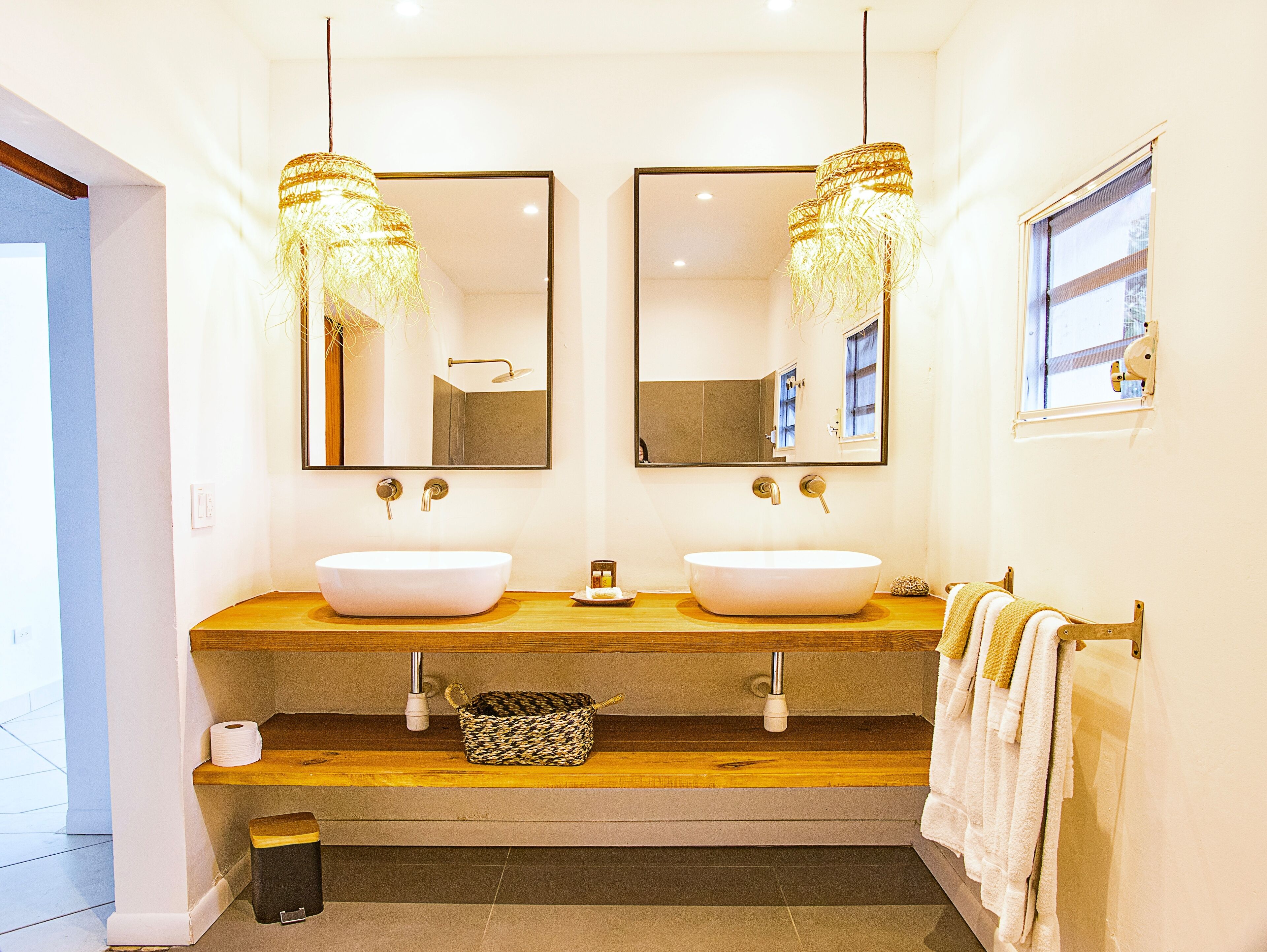 A modern bathroom with two sinks, a mirror, and a window.