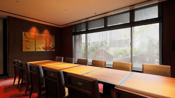 A conference room with a long table, chairs, and a large window with blinds.