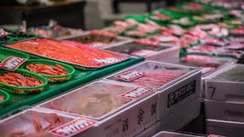 A seafood market with various containers of seafood, including shrimp and fish, displayed in green baskets and plastic containers.