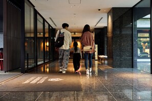 Um saguão de hotel moderno com piso lustroso, balcão de recepção e parede de vidro.