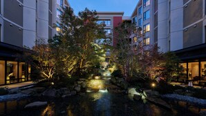 A courtyard with a water feature, stone steps, and trees.