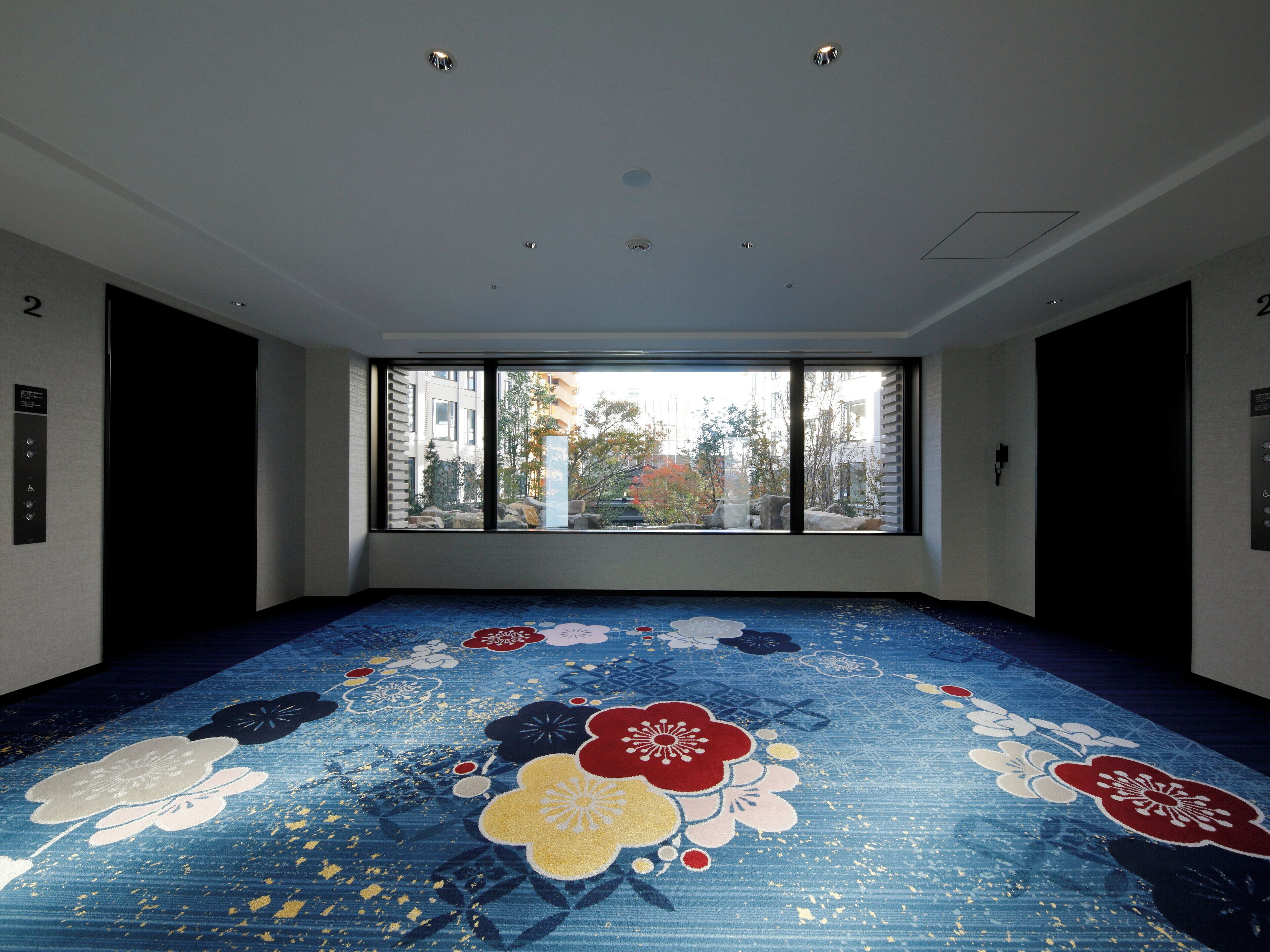 A room with a large window, a patterned floor, and a ceiling with recessed lighting.