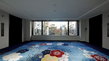 A room with a large window, a patterned floor, and a ceiling with recessed lighting.