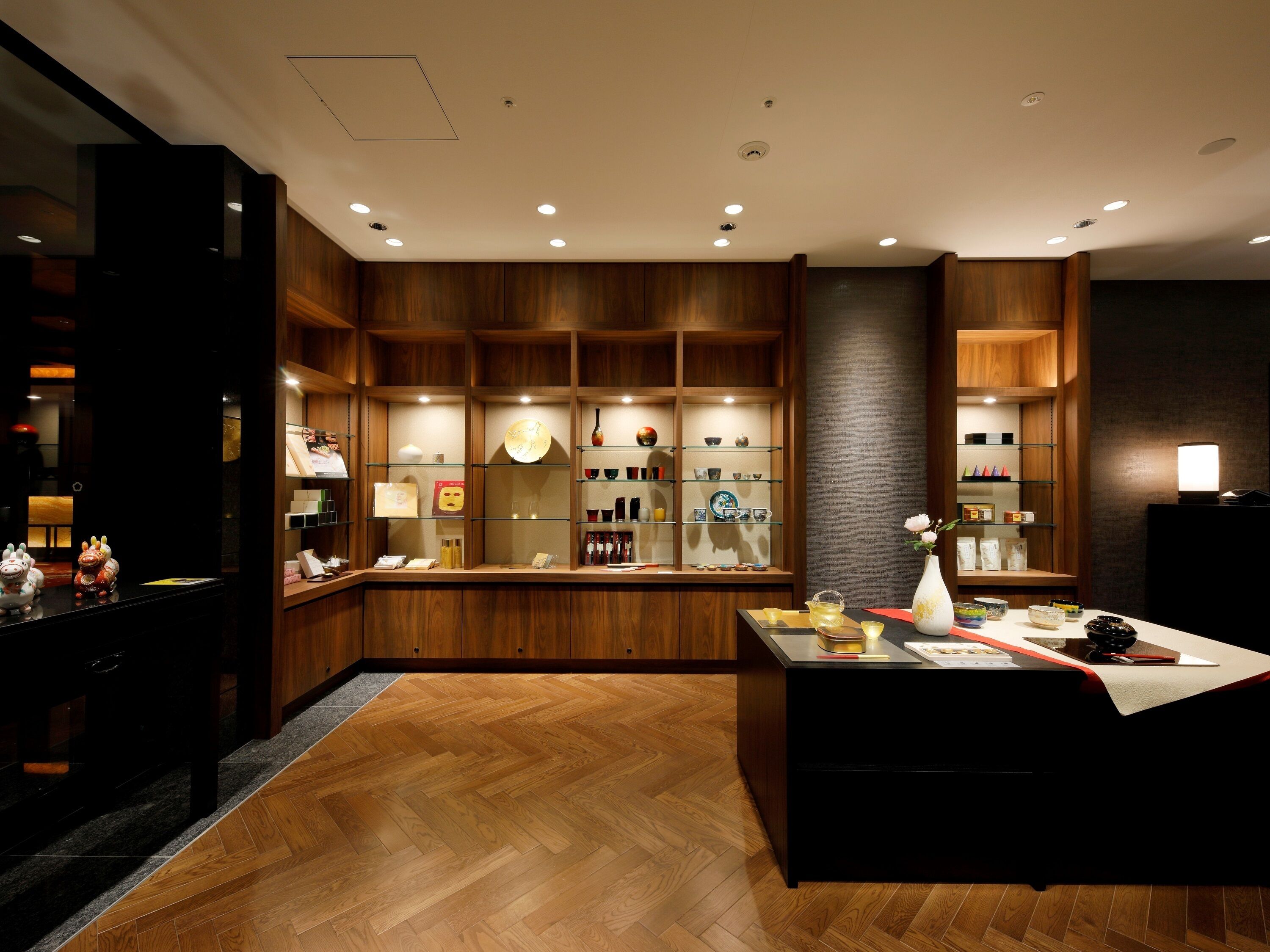 A modern hotel lobby with wooden paneling, a reception desk, and a display of local crafts.