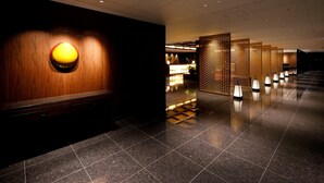 Un lobby moderno de hotel con una recepción de madera, un llamativo elemento mural iluminado y varios paneles decorativos a lo largo de la pared.