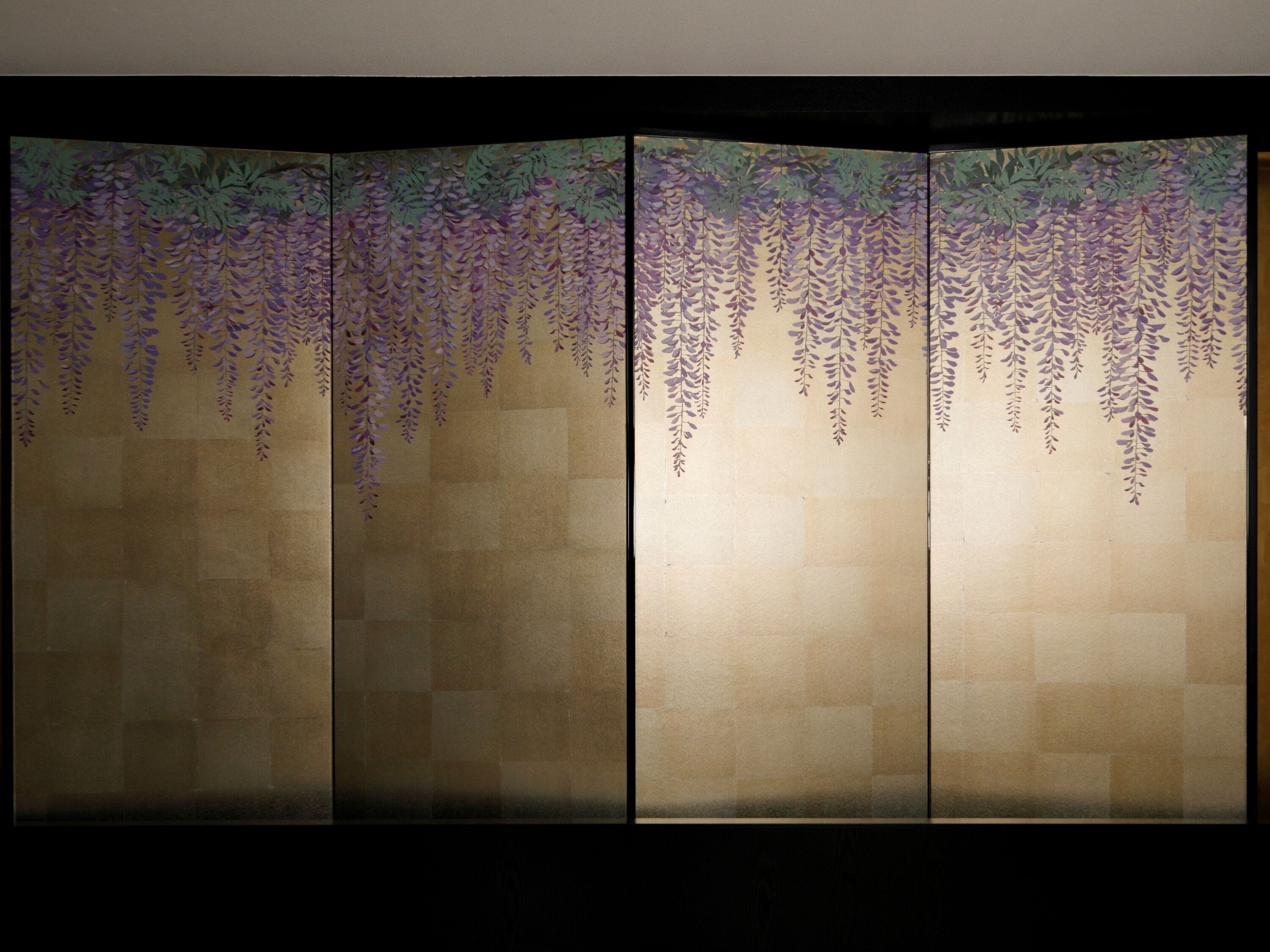 A room with a large sliding shoji screen featuring a hanging wisteria design.