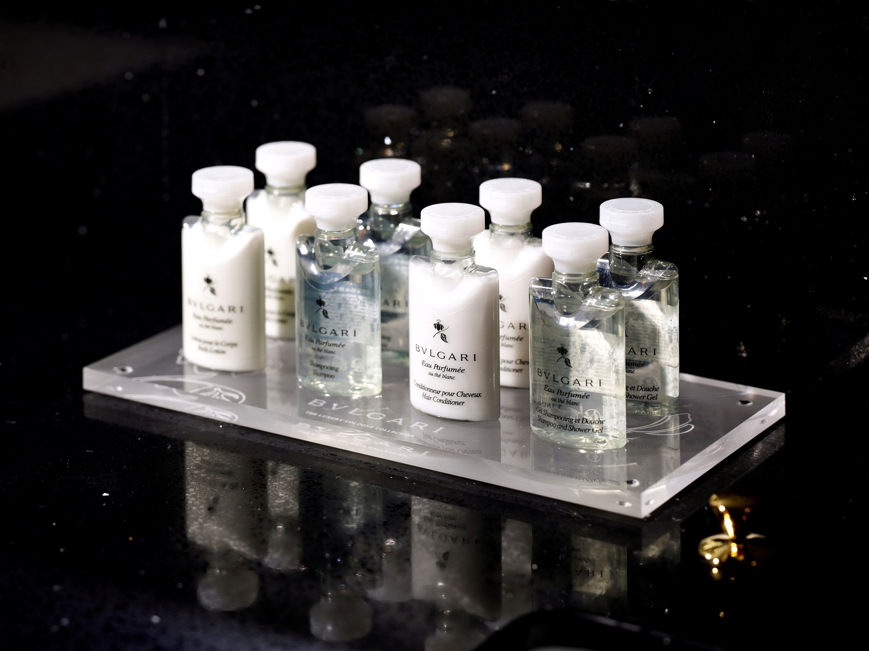 A display of BVLGARI perfume bottles on a reflective surface.