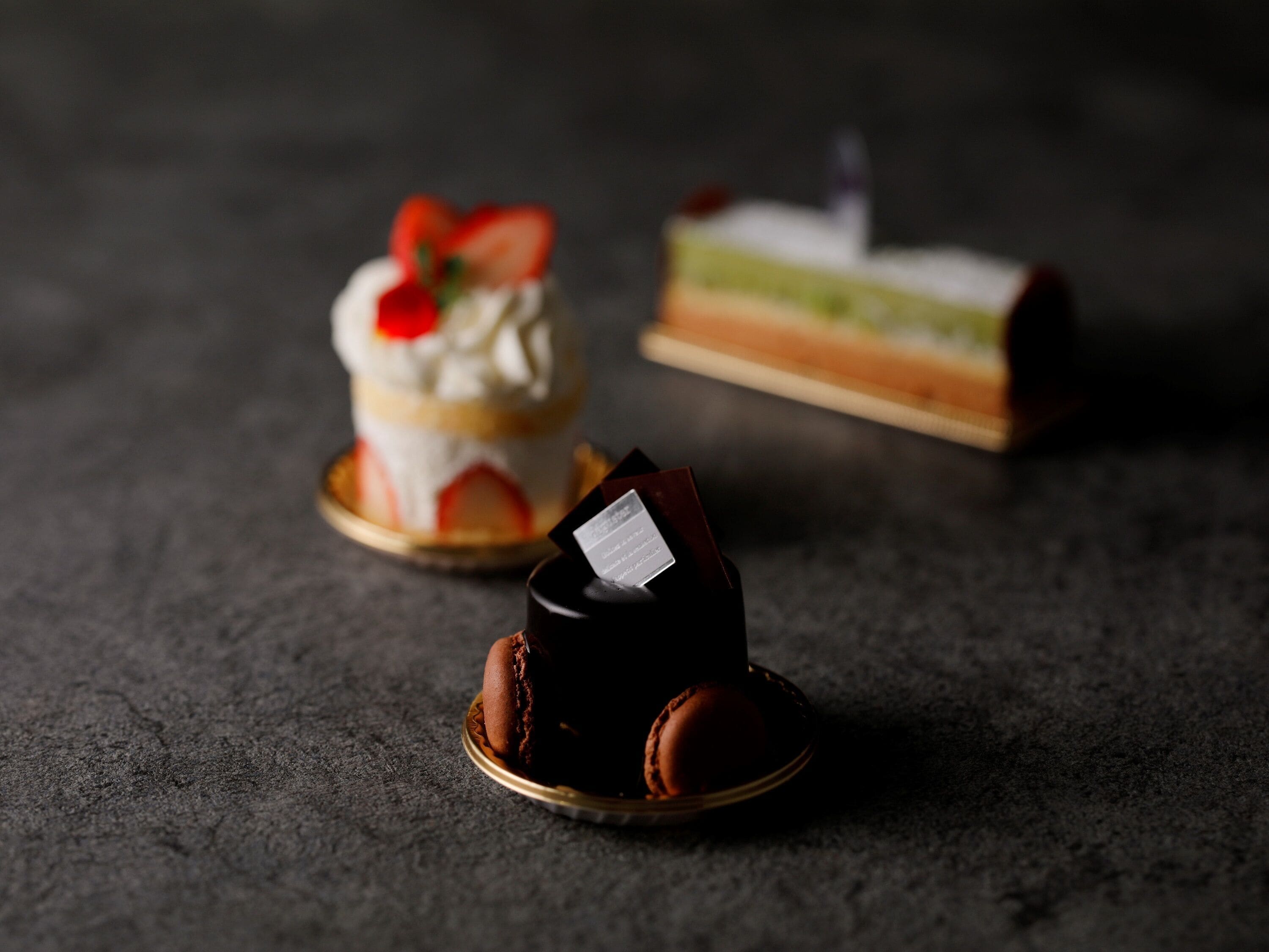 Trois desserts présentés sur une surface sombre.