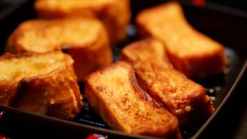 A close-up of golden-brown French toast in a black pan.