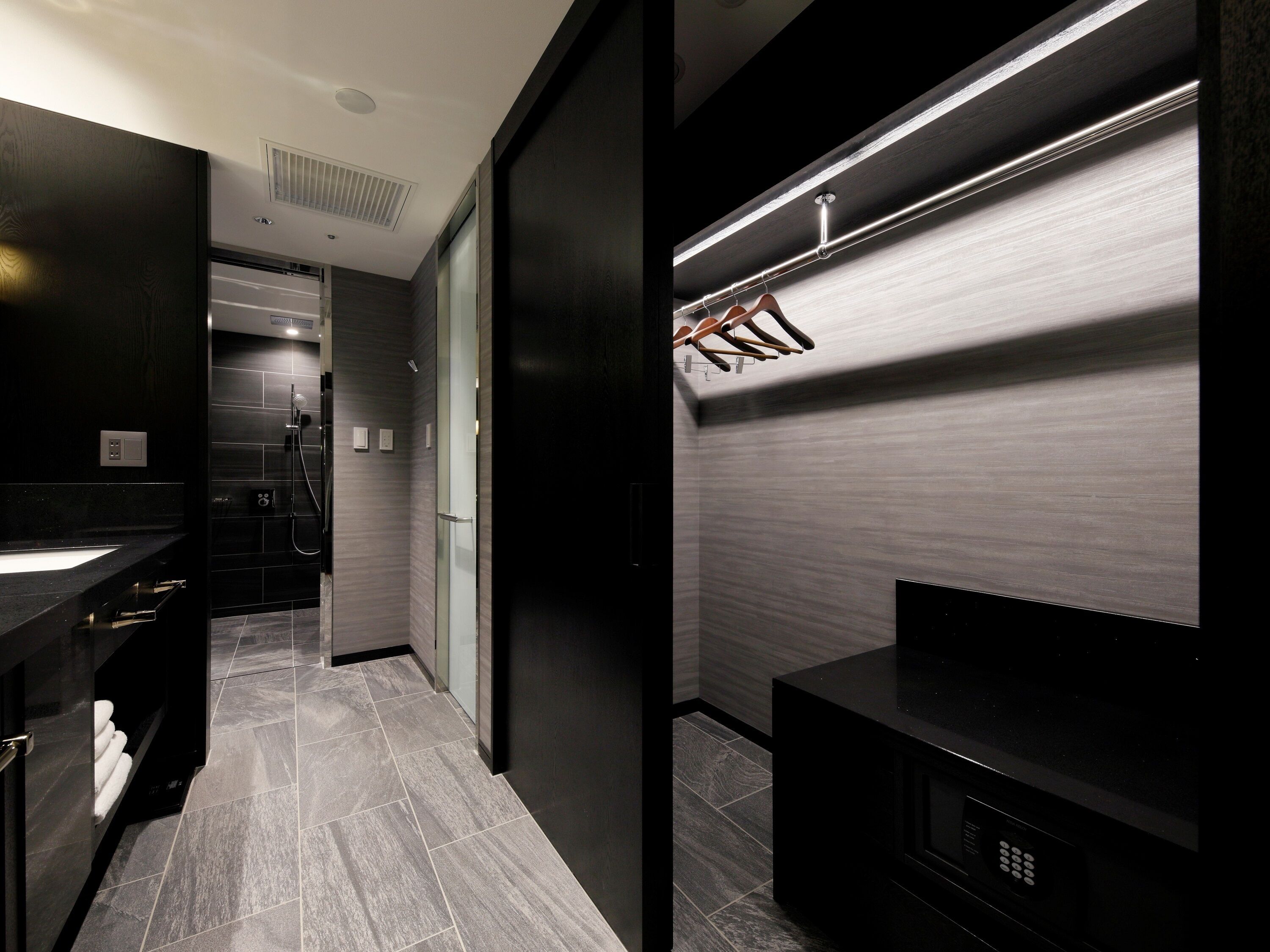 A modern bathroom with a dark wood vanity, a glass shower enclosure, and a built-in microwave.