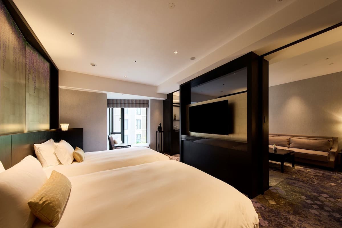 A hotel room with a large bed, a TV mounted on the wall, a sofa, and a small table.