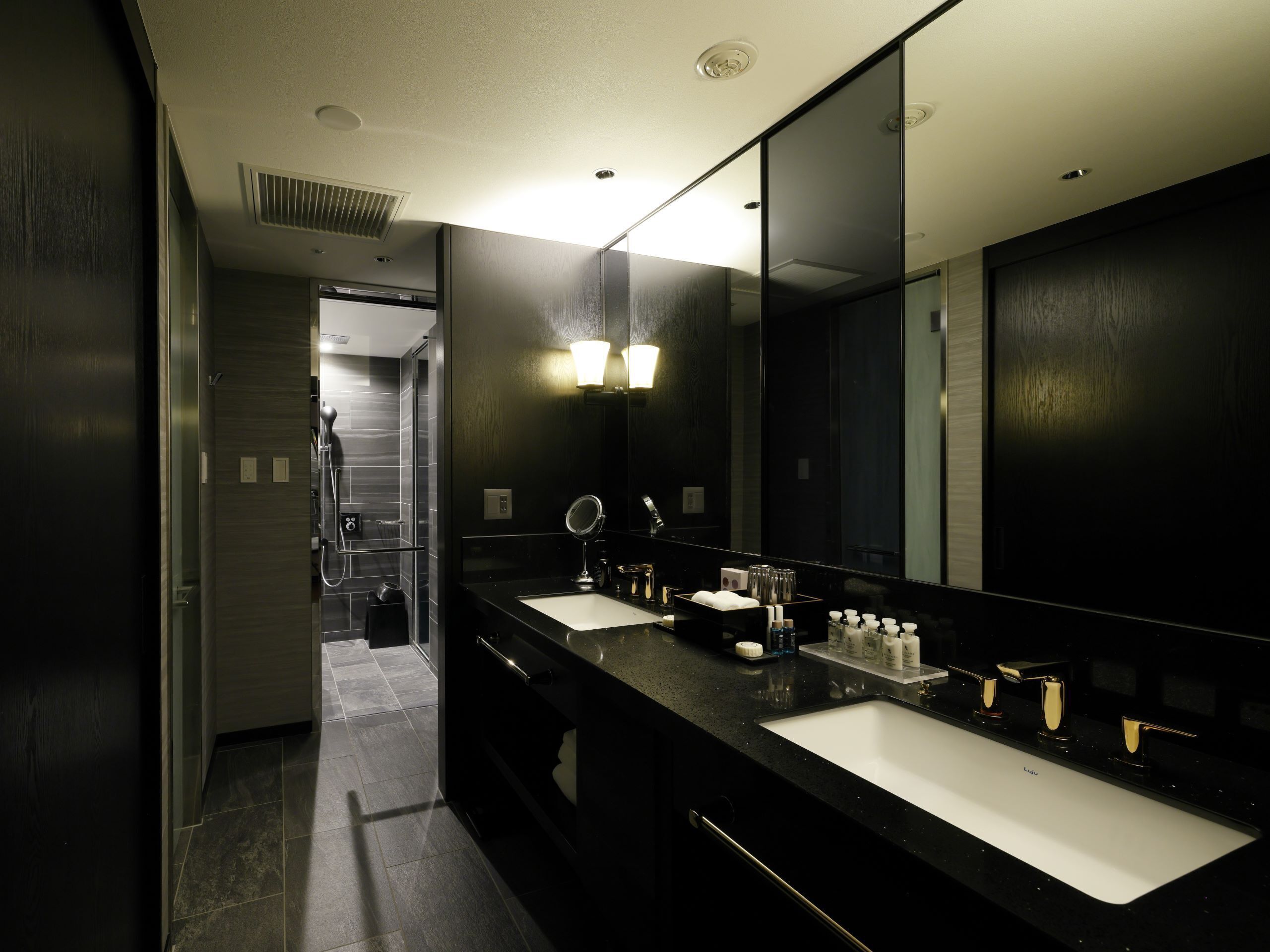 Une salle de bain moderne avec deux lavabos, un grand miroir et un espace douche.